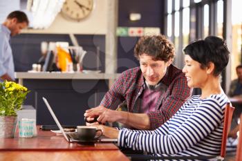 Man and woman using laptop at a coffee shop