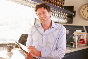 Male restaurant manager holding clipboard, portrait