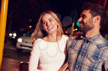 Couple walking through town together at night