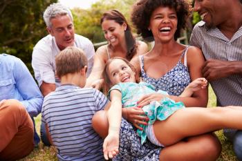 Adults and kids sitting on the grass in a garden