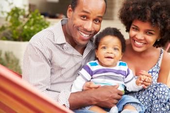 Happy couplewith young child sitting in a hammock