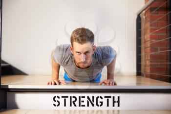 Man In Gym Doing Press-Ups On Step Labeled Strength