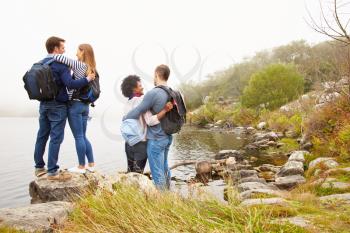 Two couples embracing by the edge of a lake