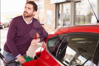 Young man refuelling a car at a petrol station