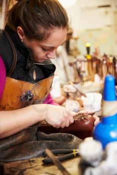 Young shoemaker working with leather in a workshop