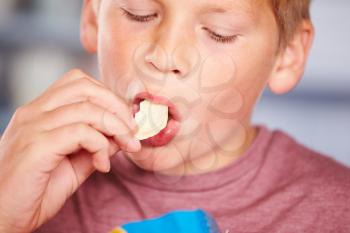 Close Up Of Boy Eating Packet Of Potato Chips