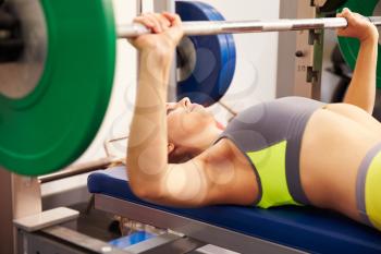 Young woman with barbellsbench pressing weights