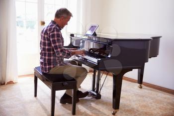 Man Learning To Play Piano Using Digital Tablet Application