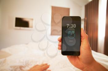 Point Of View Image Of Person In Bed Turning Off Phone Alarm