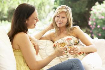 Two Female Friends Relaxing On Sofa With Glass Of Wine