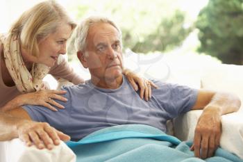 Wife Comforting Senior Man Feeling Unwell Resting Under Blanket