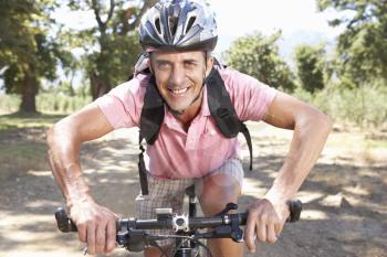 Middle Aged Man Cycling Through Countryside