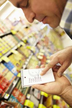 Man Looking At Shopping List In Supermarket