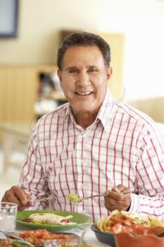 Senior Hispanic Man Enjoying Meal At Home