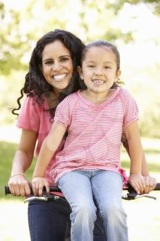 Young Hispanic Mother And Daughter Cycling In Park