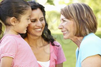 Hispanic Grandmother, Mother And Daughter Relaxing In Park