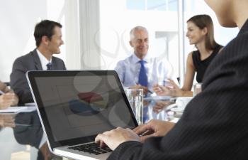 Close Up Of Businessman Using Laptop During Board Meeting Around Glass Table