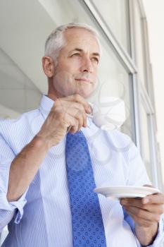 Mature Businessman Standing Outside Modern Office Drinking Coffee