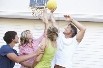 Teenage Family Playing Basketball Outside Garage