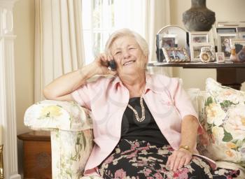 Retired Senior Woman Sitting On Sofa At Home On Phone