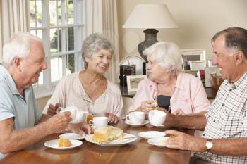 Group Of Senior Couples Enjoying Afternoon Tea Together At Home