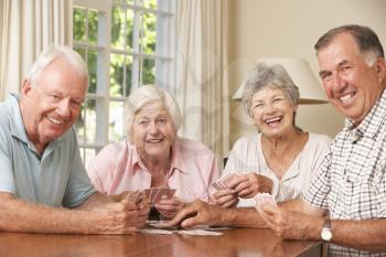 Group Of Senior Couples Enjoying Game Of Cards At Home