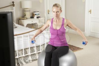 Woman Exercising Whilst Watching Fitness DVD On Television