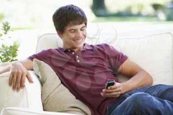 Teenage Boy Sending Text Message Sitting On Sofa