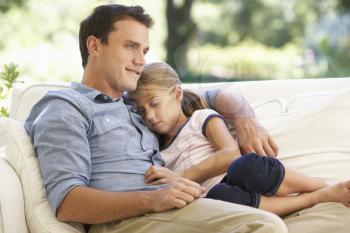 Father And Daughter Sitting On Sofa At Home