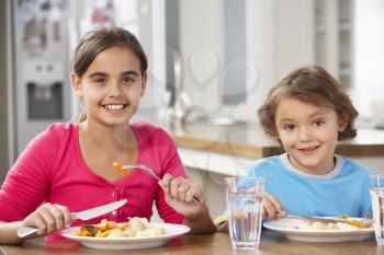 Two Children Having Meal In Kitchen Together