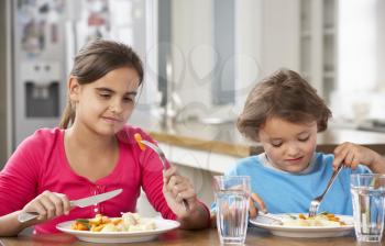 Two Children Having Meal In Kitchen Together