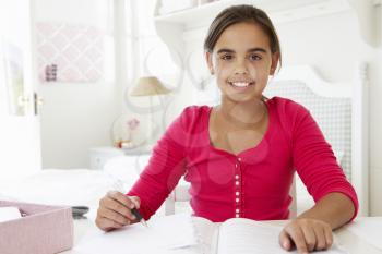 Young Girl Doing Homework At Desk In Bedroom