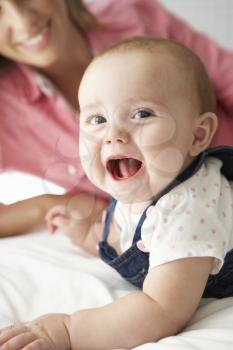 Mother With Cute Baby Girl Playing On Bed