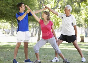 Senior Couple Working With Personal Trainer In Park