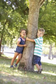 Two Children Hugging Tree In Park