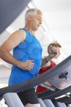 Two Men Using Running Machines In Gym