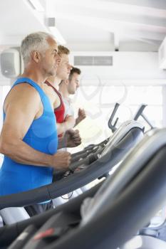 Group Of Men Using Running Machines In Gym