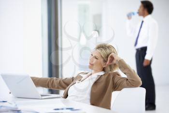 Portrait Of Female Executive Using Laptop Relaxing In Office