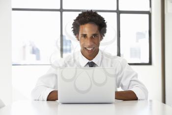 Businessman Sitting At Desk In Office Using Laptop