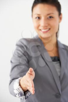Studio Portrait Of Businesswoman Reaching Out To Shake Hands