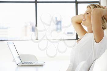 Businesswoman Sitting At Desk In Office Using Laptop