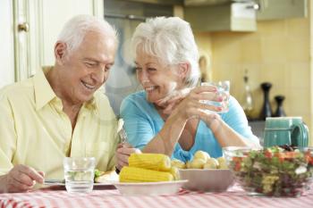 Senior Couple Eating Meal Together In Kitchen