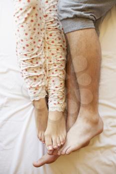 Detail Of Couple's Legs Relaxing In Bed
