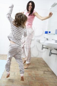 Mother And Daughter Having Fun In Bathroom Brushing Teeth