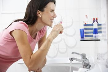 Woman In Bathroom Brushing Teeth