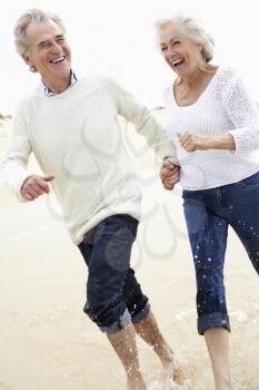 Senior Couple Running Along Beach Together