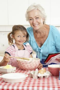 Grandmother And Granddaughter Baking In Kitchen