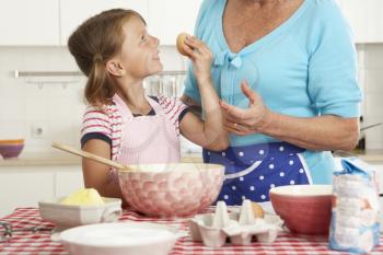 Grandmother And Granddaughter Baking In Kitchen