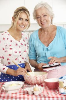 Senior Woman And Adult Daughter Baking In Kitchen