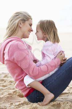 Mother And Daughter Sitting On Beach Together